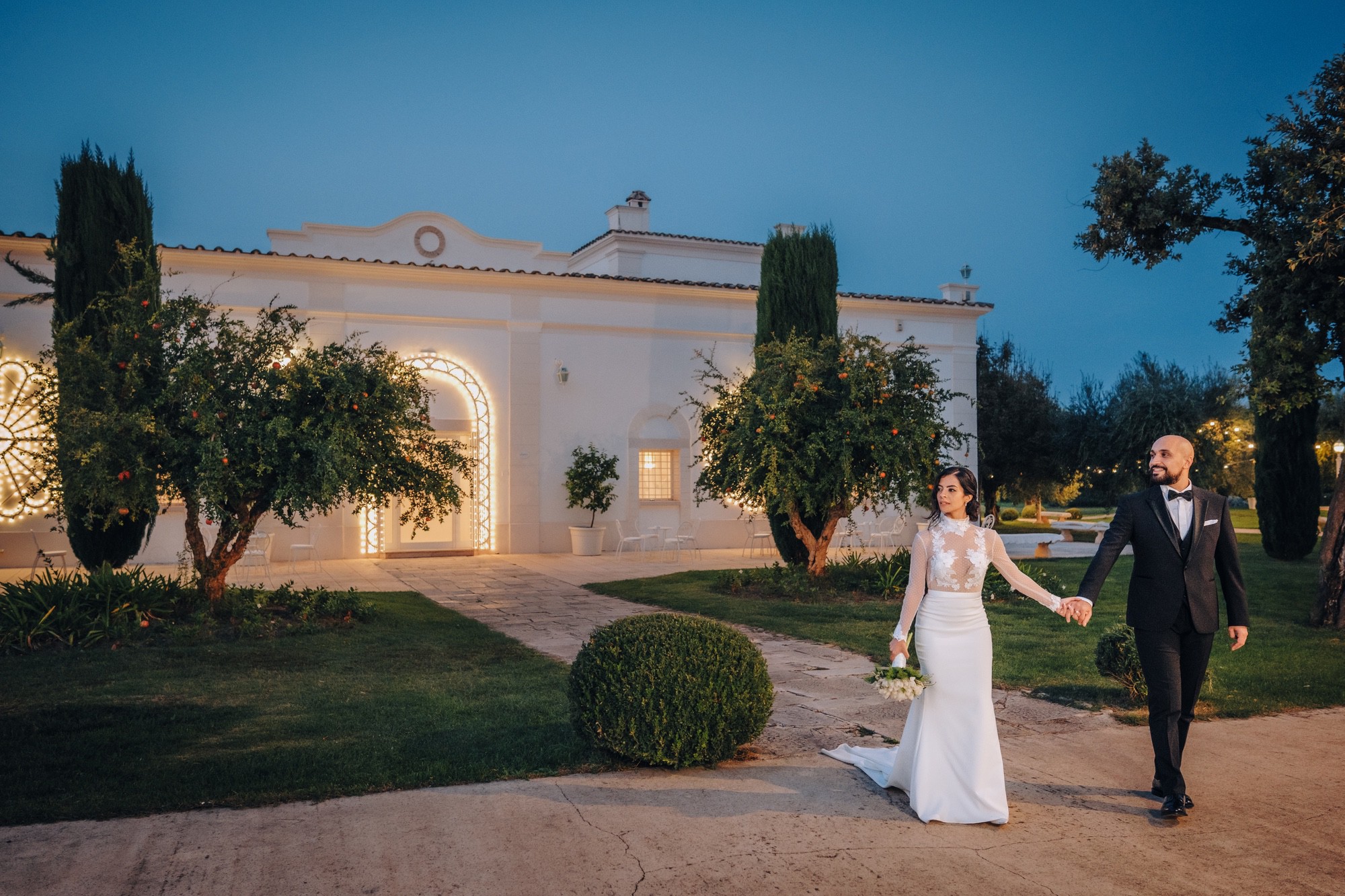 Ritratto serale di sposi nel verde della sala ricevimenti