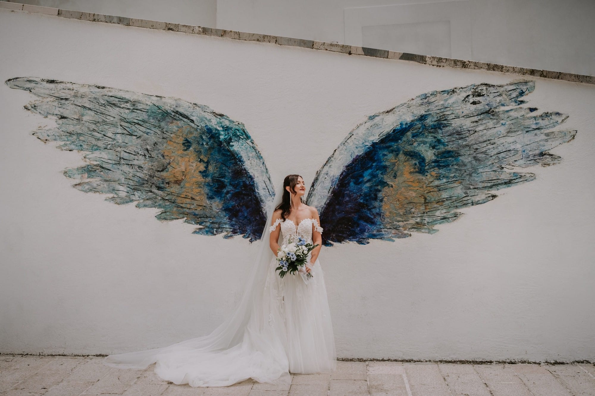 Foto di una sposa con le ali d'angelo sul muro a Monte Sant'Angelo, Foggia