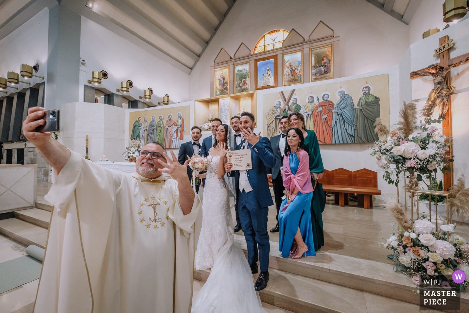 Foto di Pino Coduti con selfie prete, sposi e invitati in chiesa