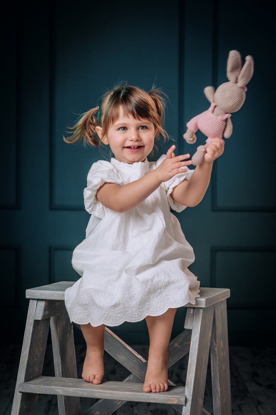 Fotoritratto di una bambina elegante che giocal con un pelouche