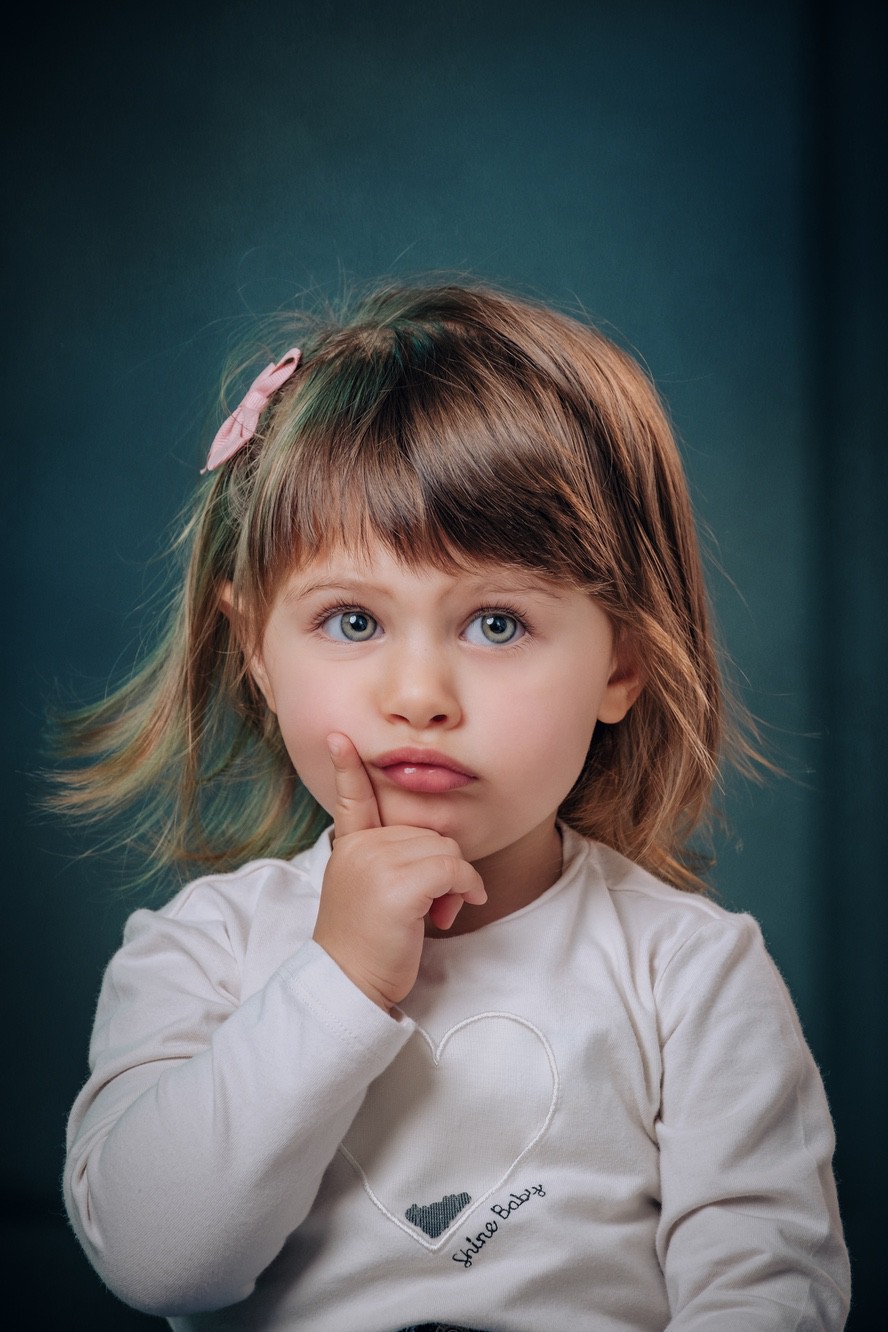 Fotoritratto di una bambina in primopiano con sguardo simpatico pensieroso