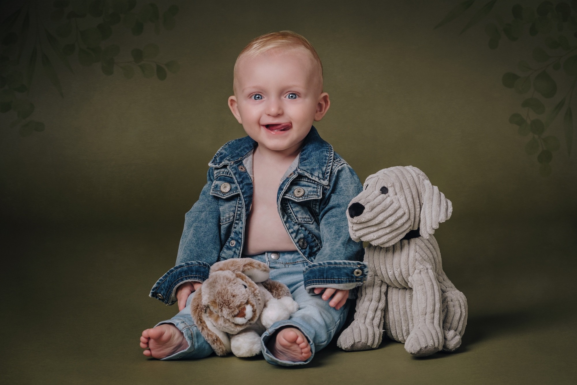 Fotoritratto di un neonato con abiti in jeans e pupazzi