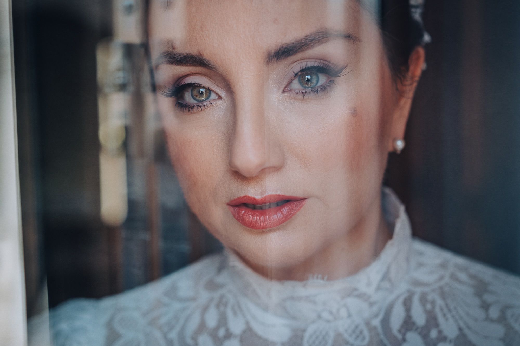 Foto di una sposa in primopiano dietro una tenda leggera