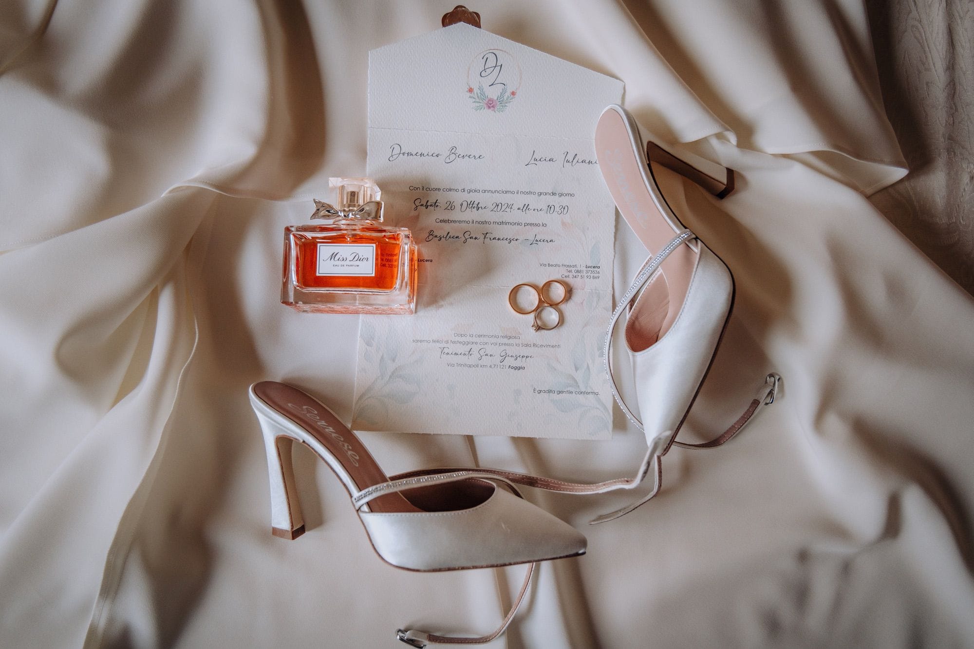 Scatto professionale di una partecipazione di nozze con profumo, anelli e scarpe femminili