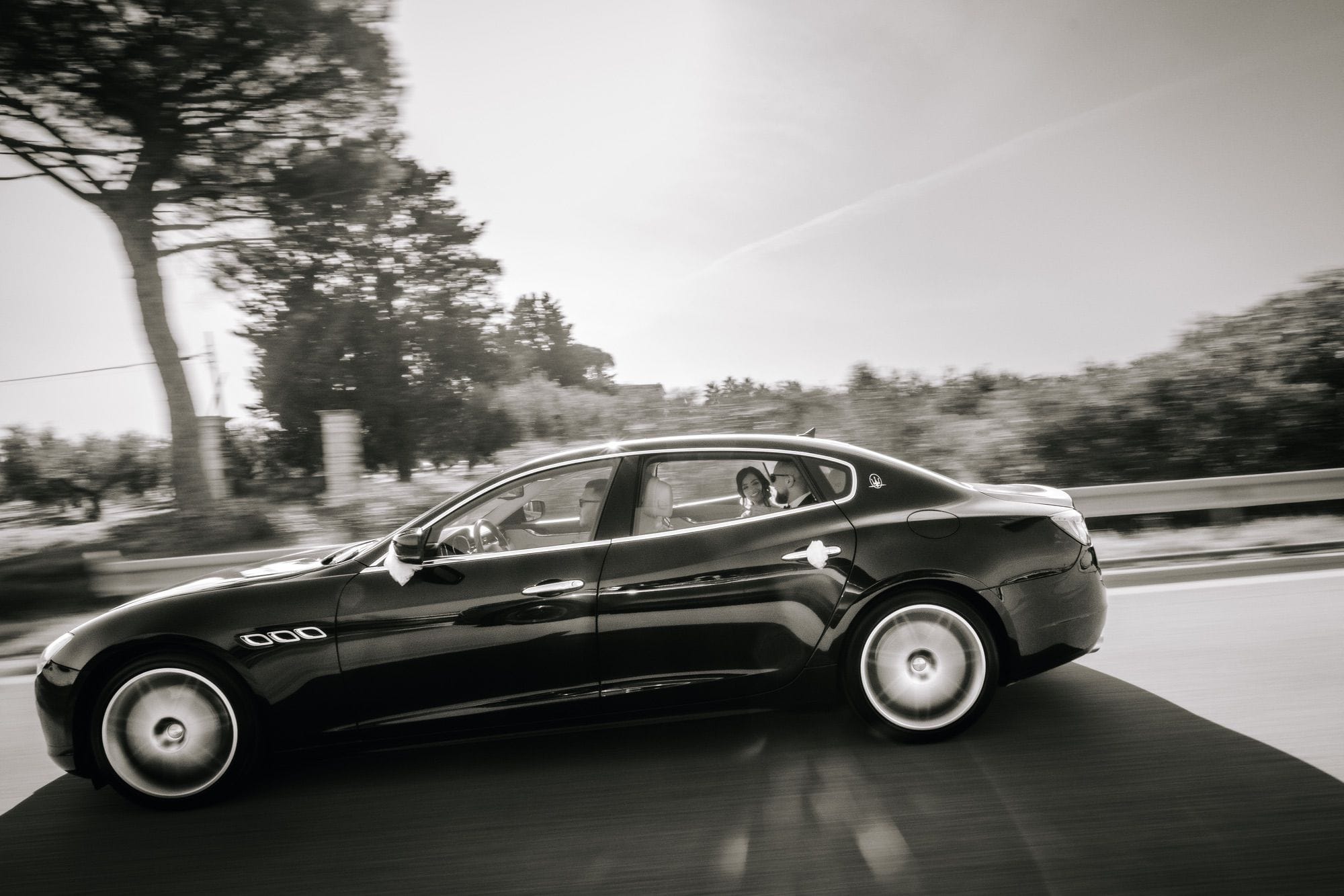 Sposi in auto elegante scura in movimento