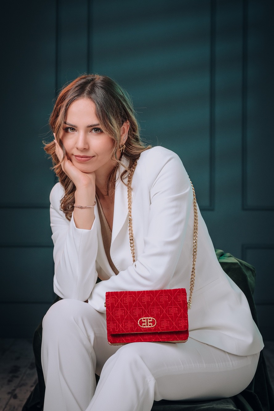 Foto ritratto professionale di iuna donna vestita di bianco con una borsa rossa.