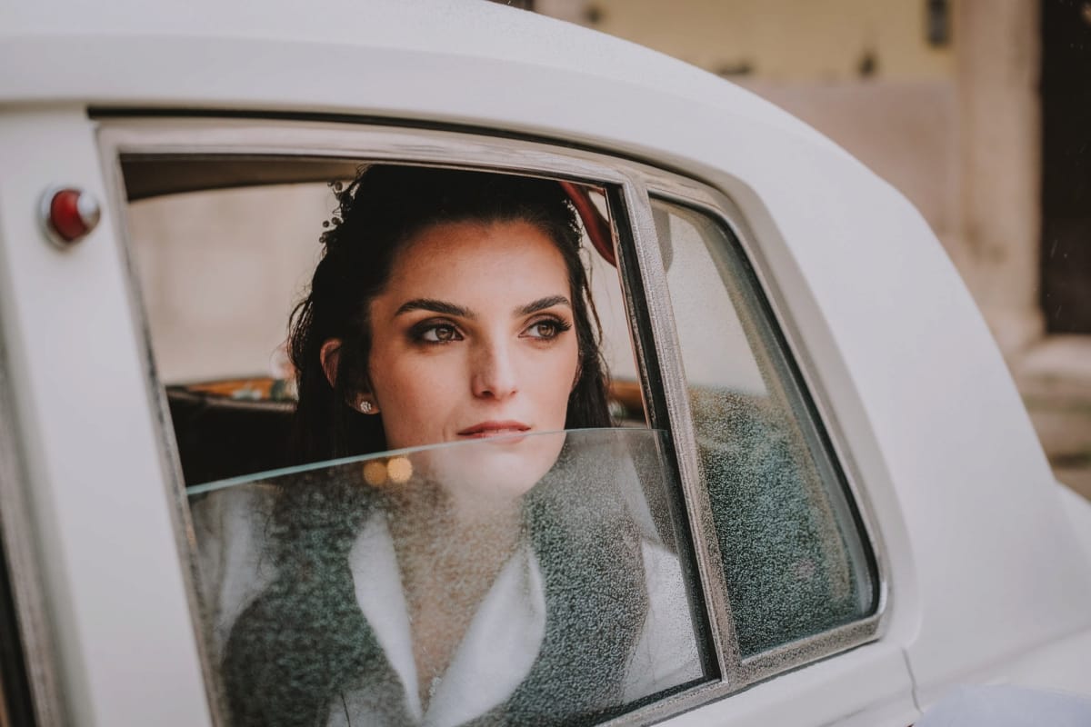 Sposa in auto d’epoca in piazza Duomo a Lucera sotto una leggera pioggia autunnale.
