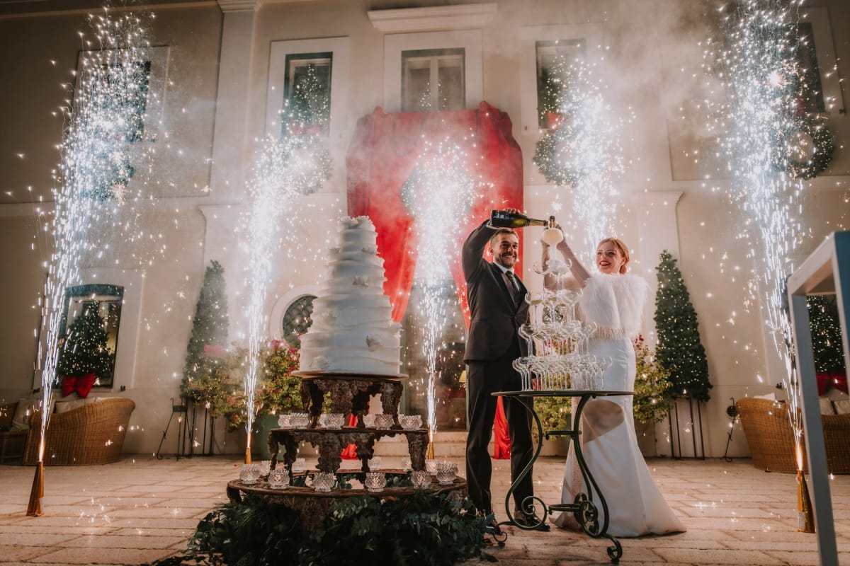 Sposi con piramide di calici con fontane pirotecniche come sfondo.