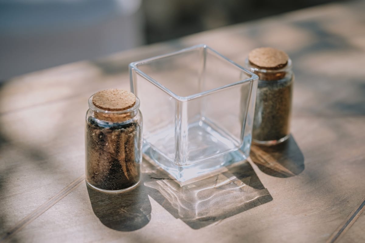 Boccette in vetro con sabbia naturale con vasetto in vetro al centro.