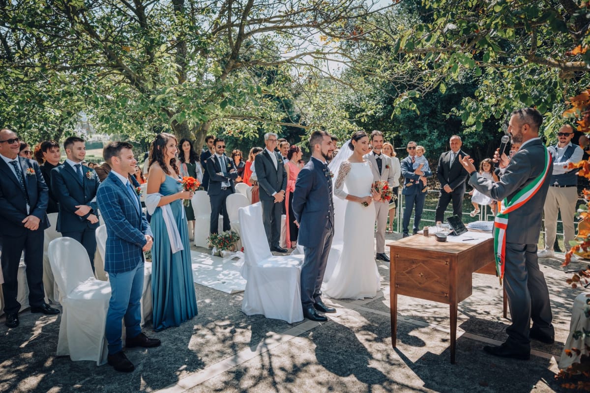 Matrimonio civile con sposi, officiante ed ospiti all'aperto.