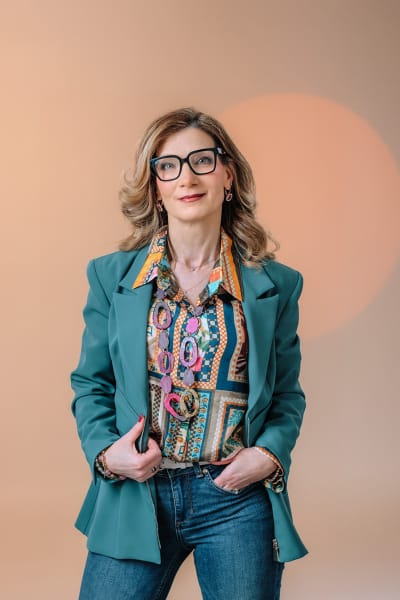Ritratto di personal branding di una professionista con blazer verde su sfondo caldo, esempio di fotografia che comunica personalità e coerenza con il ruolo